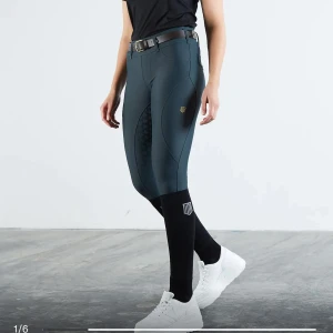 Mörkgrå ridbyxor - Snygga mörkgrå ridbyxor med hög midja och tight passform. De har en diskret logga på sidan och praktiska fickor bak. Materialet verkar vara stretchigt och bekvämt, perfekt för ridning. Byxorna har också en snygg detalj med mönstrad förstärkning på insidan av benen för extra grepp.