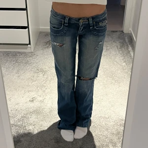 Blå jeans med slitningar - Säljer ett par snygga blå jeans med coola slitningar. De är lågmidjade och väldigt fina!! Midjemått: ca 36cm rakt över, innerbenslängd: ca 78cm💗💗✨🧘‍♀️🧘‍♀️🥹🥹
