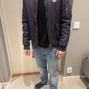 Svart bomberjacka från Morris - Säljer en snygg svart bomberjacka från Morris i storlek medium. Jackan har en quiltad insida och är perfekt för höst och vår. Den har långa ärmar och en dragkedja framtill. Perfekt för en casual look eller en utekväll!