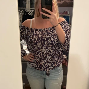 Mönstrad offshoulder topp - Säljer en snygg offshoulder topp med ett mönster i lila och vitt. Perfekt för både vardag och fest! Toppen har långa ärmar och en avslappnad passform. Den är superbekväm och lätt att matcha med jeans eller kjol. Köparen står för frakten💕