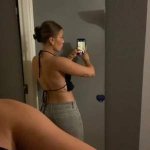 Svart halterneck topp från Gina Tricot - Snygg svart halterneck topp från Gina Tricot i återvunnen polyester. Toppen har en volangdetalj och är perfekt för sommarens fester. Den är ärmlös och knyts i nacken, vilket ger en öppen rygg. Passar för personer i xs/s.