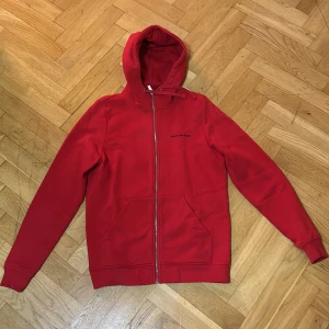 Röd hoodie från Race Marine - Säljer en snygg röd hoodie från Race Marine i storlek S. Den har en dragkedja framtill och en praktisk huva. Perfekt för både höst och vår, och den är i mycket bra skick. Passar perfekt för en casual look eller träning.