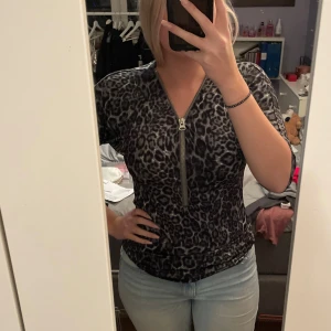 Leopardmönstrad topp med dragkedja - Snygg leopardmönstrad topp med en dragkedja framtill. Den är tight och har korta ärmar, perfekt för en utekväll eller fest. Materialet känns mjukt och stretchigt, vilket gör den bekväm att bära hela dagen. Köparen står för frakten💖