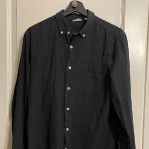 Svart skjorta stl M dobber - säljer denna svarta skjorta med vita knappar.  från dobber i stl M. Skjortan är lite skrynklig eftersom den legat i en låda men annars är den helt ny i skick.