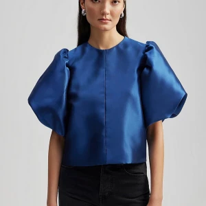 By Malina Blå satinblus med puffärmar - Snygg blå blus i satin med puffiga kortärmar. Perfekt för en festlig kväll eller en stilren vardagslook. Blusen har en elegant och glansig finish som ger en lyxig känsla. Nypris: 2200:- 