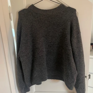 Grå stickad tröja från H&M - Mysig grå stickad tröja från H&M i storlek S. Perfekt för kyliga dagar med sin mjuka och varma känsla. Tröjan har en normal passform och långa ärmar, vilket gör den idealisk för både höst och vinter. Ett måste i garderoben för en stilren och bekväm look!