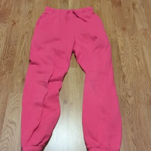 Rosa mjukisbyxor - Säljer ett par sköna rosa mjukisbyxor i bra skick. Perfekta för en chill dag hemma eller en avslappnad promenad. Byxorna har en elastisk midja med snörning för bästa passform. De är loose fit och gjorda i mjukt material för extra komfort.