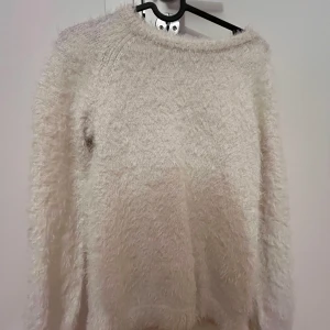 Vit fluffig tröja - Mysig och fluffig vit tröja perfekt för kyliga dagar. Den har en enkel design med långa ärmar och en rund halsringning. Tröjan är supermjuk och känns som att ha på sig ett moln. Perfekt för både vardag och mysiga hemmakvällar.