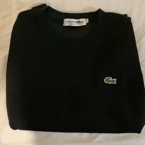 Svart Lacoste sweatshirt  - Säljer en klassisk svart tröja från Lacoste i storlek s/m. Tröjan  är i mycket bra skick. Passar bra till höst och vinter.(Priset kan diskuteras) Finns också i färg mörkblå