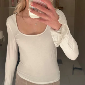 Vit långärmad topp från Bik Bok - Säljer en stilren vit långärmad topp från Bik Bok. Den har en enkel och klassisk design med rund halsringning, perfekt för både vardag och fest. Materialet är mjukt och bekvämt, vilket gör den idealisk för alla säsonger.