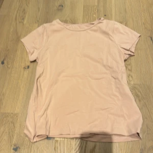 Rosa t-shirt från KappAhl - Säljer en enkel och stilren rosa t-shirt från KappAhl i ekologisk bomull. Perfekt för vardagsbruk med en normal passform och korta ärmar. Skön och mjuk, passar till det mesta i garderoben!🩷