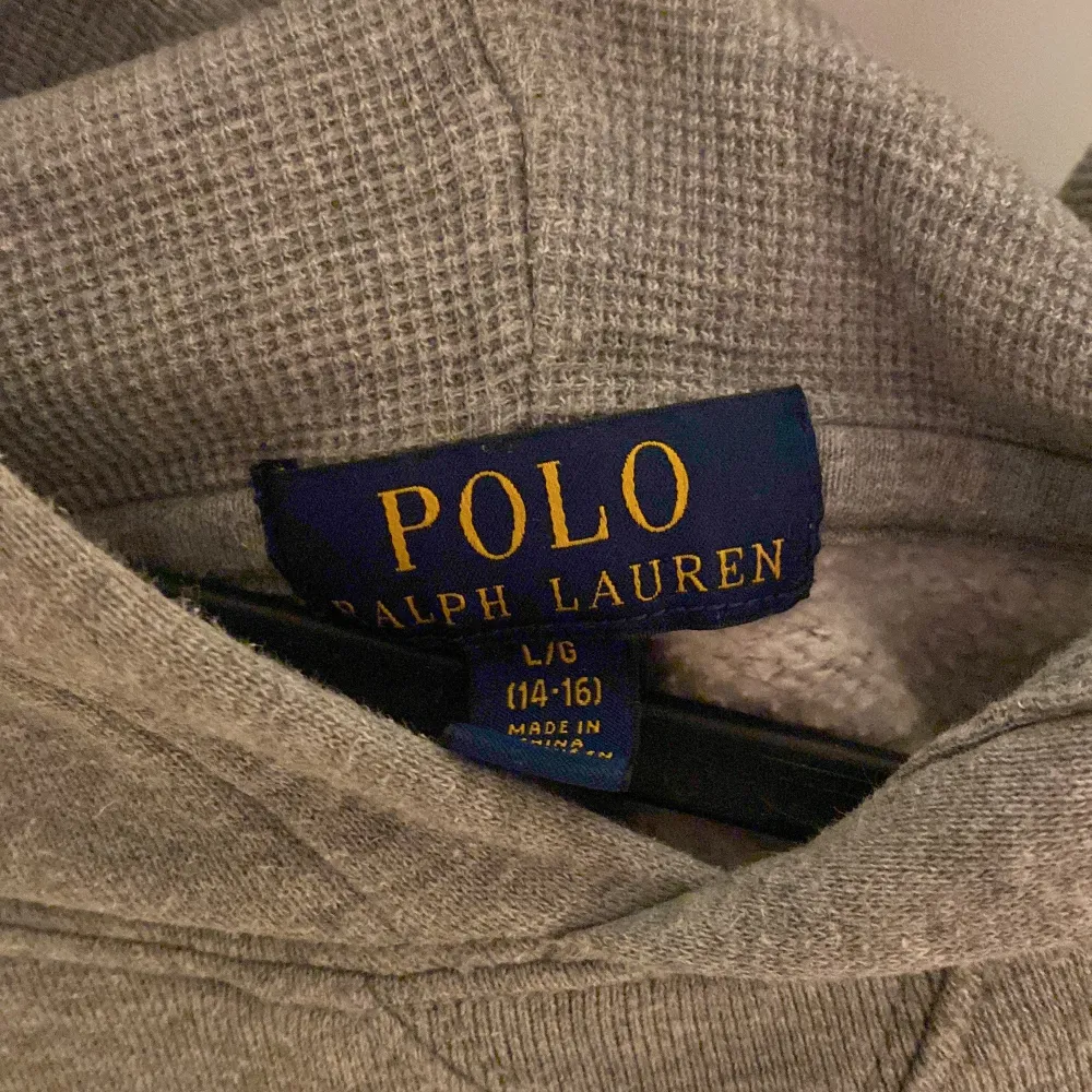 Säljer en snygg och bekväm grå hoodie från Polo Ralph Lauren. Den har en klassisk design med en liten logga på bröstet och en stor ficka framtill. Perfekt för kyliga dagar eller mysiga hemmakvällar. Passar till det mesta i garderoben!. Tröjor & Koftor.