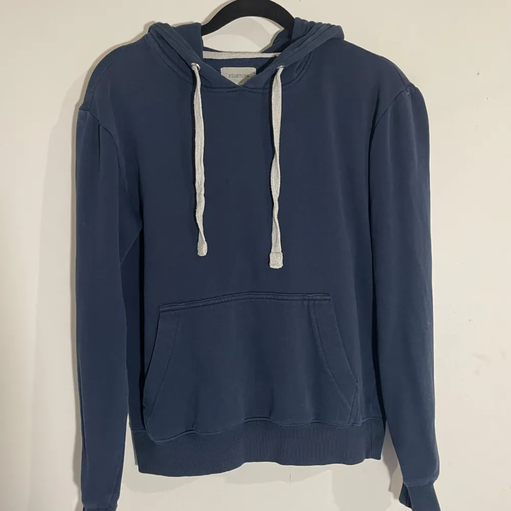 Säljer en snygg mörkblå hoodie från Yourturn i storlek XS. Den har en klassisk design med känguruficka och justerbar huva med vita snören. Perfekt för en avslappnad stil under höst och vår. Hoodien är i bra skick och redo för nya äventyr!. Hoodies.