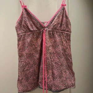 Mönstrad linne från Juicy Couture - Säljer en söt linne från Juicy Couture i storlek S. Den har ett färgglatt hjärtmönster i rosa och andra nyanser, med smala axelband och en söt rosett framtill. 