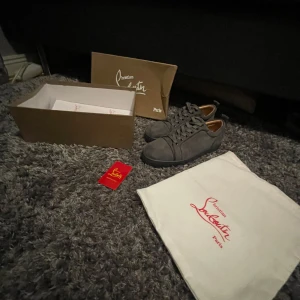 Grå sneakers från Christian Louboutin - Säljer ett par grå sneakers från Christian Louboutin i mocka med den ikoniska röda sulan. Skorna har snörning och är i mycket bra skick. Perfekta för både vardag och fest! Kommer med originalförpackning och dustbag. Endast testade inomhus 10/10 skick