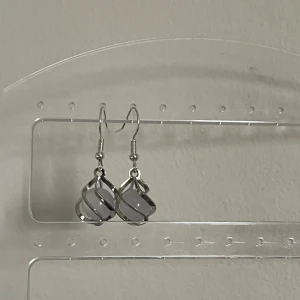 Silvriga örhängen med vit pärla - Snygga silvriga örhängen med en vit pärla inuti en spiralformad design. Perfekta för att ge en elegant touch till vilken outfit som helst. Passar både till vardag och fest!