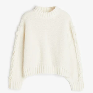 Vit stickad tröja med flätade detaljer - Superfin vit stickad tröja med flätade detaljer längs ärmarna. Den har en mysig och varm känsla, perfekt för kyliga dagar. Tröjan har en ribbad kant vid halsen, ärmsluten och nederkanten. Perfekt för både vardag och mysiga hemmakvällar!