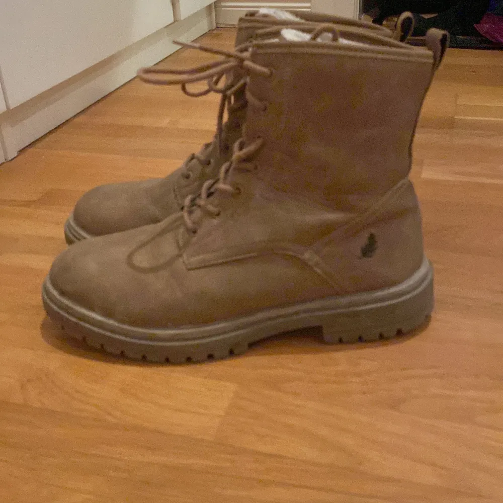 Säljer ett par bruna boots från Rest i bra skick. De är i storlek 41 och har en robust design med snörning framtill. Perfekta för höst och vinter med sitt varma foder. Skorna är tillverkade i ett slitstarkt material som passar för kyligare väder.. Skor.