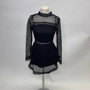 Svart spetsklänning - Snygg svart spetsklänning med långärmad design och en tight passform. Klänningen har ett vackert spetsmönster och är perfekt för festliga tillfällen. Den är kort och har en elegant stil som verkligen sticker ut.