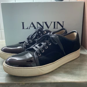 Lanvin Skor - Säljer ett par stilrena svarta sneakers från Lanvin. Storlek 42-43/UK 8. Inga skador på skorna, box och extra sko snören följer med. Skriv för fler frågor!
