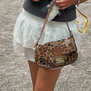 Leopardmönstrad axelväska - Vintage Fendi väska i kalvskinn med leopard mönster. Riktig statemenr väska som gett mig massa komplimanger. Tecken på användning som syns på bilder, inget man tänker på när man bär väskan. Väskan har ett snyggt brunt läderband och en stilren metallspänne framtill. Perfekt för att ge din outfit en vild touch! 🐆