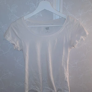 Vit t-shirt från 157 - Säljer en enkel och stilren vit t-shirt från 157 i storlek XS. Den är gjord av bomull och har en rund halsringning med korta ärmar. Perfekt basplagg för vardagsbruk!🤍