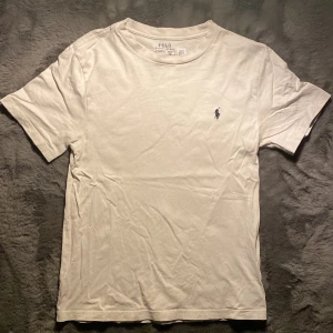 Vit t-shirt från Ralph Lauren - Säljer en vit t-shirt från Ralph Lauren i storleken 10-12 som är runt 162 skulle jag säga! Den ganska använd men har inga fläckar vad jag har sett! Skriv för fler bilder eller frågor och funderingar!