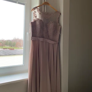 Champagnefärgad långklänning med spetsdetaljer - Säljer den fina klänning som bara används en gång i några timmar. Passar 40-44. Perfekt för festliga tillfällen som bal eller bröllop.