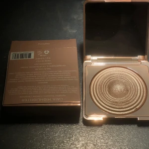 Portofino highlighter ifrån CAIA. Helt ny, kan se logoet - Snygg guld highlighter med en skimrande finish. Kommer i en elegant förpackning med spegel. Perfekt för att ge ansiktet en strålande glöd.
