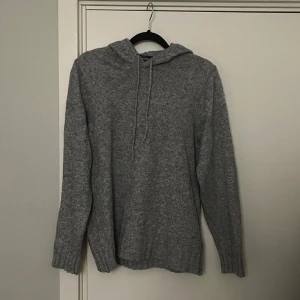 Grå stickad hoodie  - Mysig grå stickad hoodie från Dressmann i storlek S. Den har en klassisk design med ribbade muddar och en praktisk huva. Den säljs inte längre och är därför svår att få tag på.