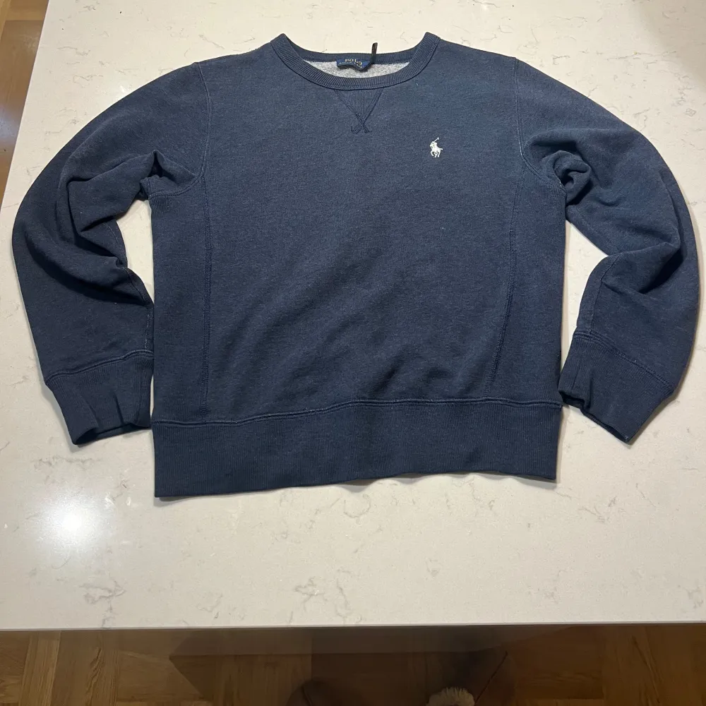 Tjena, säljer en snygg mörkblå sweatshirt från Ralph Lauren i mycket bra skick. Tröjan har en liten broderad logga på bröstet och är perfekt för både vardag och avslappnade tillfällen. Den är gjord i mjukt material och har ribbade muddar vid ärmslut och nederkant.. Tröjor & Koftor.