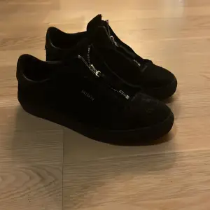 Säljer ett par svarta sneakers från Axel Arigato i mycket bra skick. De har en stilren design med dragkedja istället för snörning, vilket ger dem en unik look. Perfekta för både vardag och fest! 🖤