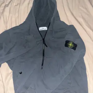 Säljer en snygg grå hoodie från Stone Island i mycket bra skick. Den har en dragkedja framtill och en klassisk logga på ärmen. Perfekt för höst och vår, och den är superbekväm att ha på sig. Passar både till vardags och chillkvällar. Vet ej om den e äkta, köpt här på plick men annars en bra k0pi@