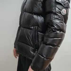 Säljer en snygg svart pufferjacka från Moncler i mycket bra skick. Jackan är perfekt för vintern med sitt quiltade mönster och långa ärmar. Den har en dragkedja framtill och två praktiska fickor med dragkedja. Supervarm och stilren för kalla dagar! 🖤