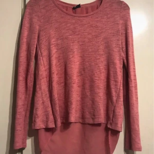 Rosa tröja från Gina Tricot - Säljer en snygg rosa tröja från Gina Tricot i storlek S. Tröjan har en unik design med en slits baktill och är tillverkad i mjukt polyester- och viskosmaterial. Perfekt för både vardag och fest! 💖