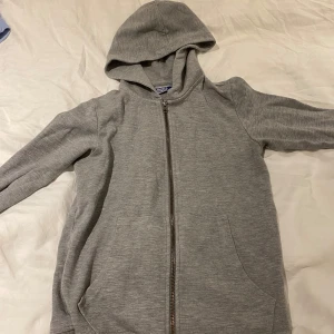 Grå kofta från Jack & Jones - Säljer en grå kofta från Jack & Jones i mycket bra skick. Perfekt för kyliga dagar eller som ett extra lager. Passar till både vardag och träning.