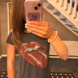 Grå t-shirt med glittrigt mönster - Säljer en grå t-shirt med ett coolt glittrigt mönster.  Några av paljetterna har lossnat men inget som uppmärksammas.