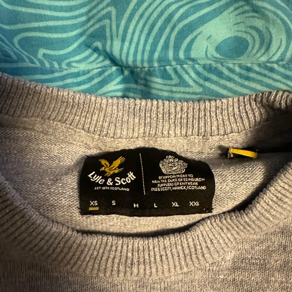 Säljer en stilren grå tröja från Lyle & Scott i bra skick. Den har en liten broderad logga på bröstet och är perfekt för både vardag och lite finare tillfällen. Tröjan är långärmad och gjord i ett mjukt material som känns skönt mot huden. Strl 170 S. Neuletakit & Villapaidat.