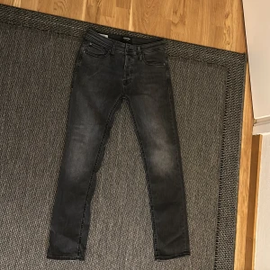 Jack & Jones jeans - Säljer ett par snygga mörkgråa jeans från Jack & Jones i storlek 28/30. De har en slim passform och är i ny skick.