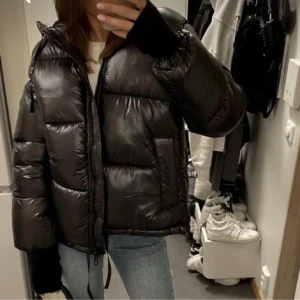 Svart pufferjacka - Säljer en snygg svart pufferjacka i glansigt material. Jackan har en dragkedja framtill och är perfekt för kalla dagar. Den är långärmad och har en skön, vadderad känsla. Passar perfekt till både vardag och fest! Slutsåld från hm❤️