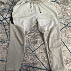 Nike tech tracksuit pris kan diskuteras  - Säljer ett par grå mjukisbyxor från Nike i mycket bra skick. De har en elastisk midja med snörning och en avslappnad passform. Perfekta för träning eller en chill dag hemma. Byxorna har en snygg design med svarta detaljer på sidorna.