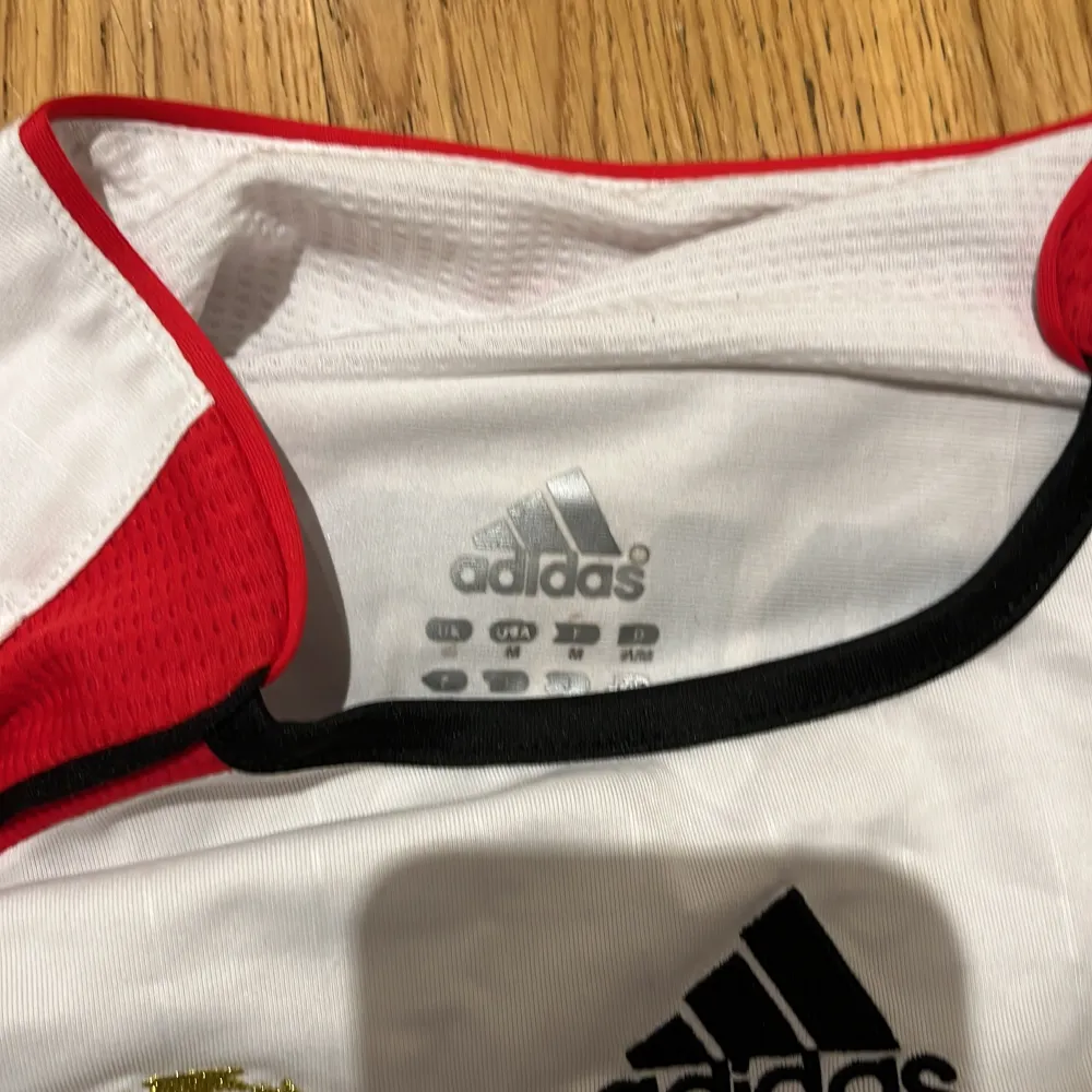 Säljer en vit långärmad AC Milan tröja från Adidas i mycket bra skick. Den har röda och svarta detaljer med klubbens emblem och Champions League-märke. På baksidan står det 'Maldini' och nummer 3. Perfekt för samlare eller fans! ⚽. T-shirts.