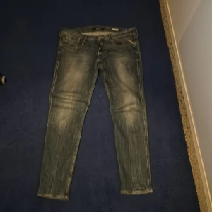 Replay anbass jeans - Säljer ett par grå jeans i bra skick. De har en snygg, sliten look och är perfekta för vardagsbruk. Passformen är slim och de har en klassisk femficksdesign. Perfekta för både höst och vår!