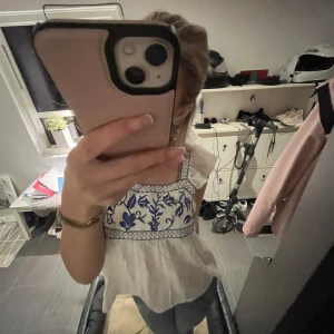 Vit blus med blått broderi - Säljer en superfin vit blus med blått blommigt broderi. Den har breda axelband och en luftig passform, perfekt för sommardagar. Blusen är i mycket bra skick och passar både till vardags och festligare tillfällen. Perfekt att matcha med jeans eller kjol! Aldrig använd och i jätte bra skick 