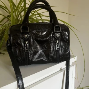 Svart handväska från Zadig & Voltaire - Snygg svart handväska i skinn från Zadig & Voltaire. Den har två dragkedjor framtill och en justerbar axelrem med märkets logga. Perfekt för både vardag och fest!