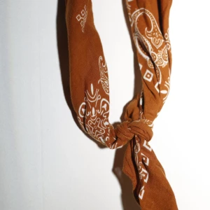 Brun bandana med paisleymönster - Säljer en snygg brun bandana med klassiskt paisleymönster i vitt. 