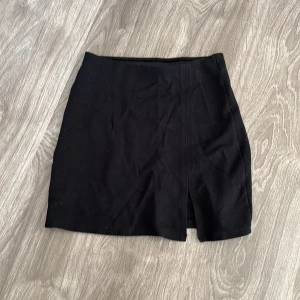 Svart kortkjol med slits - Snygg svart kortkjol i ett stilrent och klassiskt snitt. Kjolen har en diskret slits framtill som ger en extra touch. Perfekt för både vardag och fest! 🖤