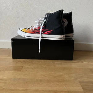 Svarta sneakers med eldflamma-design - Säljer ett par coola svarta sneakers med en eldflamma-design i rött.