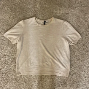 Beige kortärmad tröja från H&M Divided - Säljer en stilren beige kortärmad tröja från H&M Divided. Perfekt för en avslappnad look, med ribbade kanter vid ärmar och nederkant. Tröjan är i bra skick och passar till både vardag och fest. Skön och enkel att matcha med andra plagg! Är en magtröja!! Pris kan diskuteras.