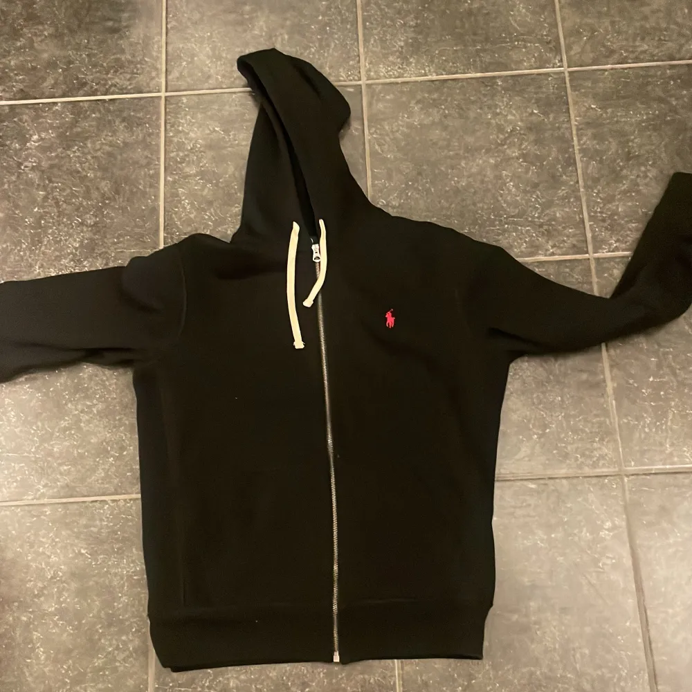 Säljer en snygg svart hoodie från Ralph Lauren i storlek M. Den har en dragkedja framtill och en klassisk röd logga på bröstet. Han på bilden är mellan 180-185cm. Tröjan är i nyskick och kostar 2300kr ny.. Tröjor & Koftor.